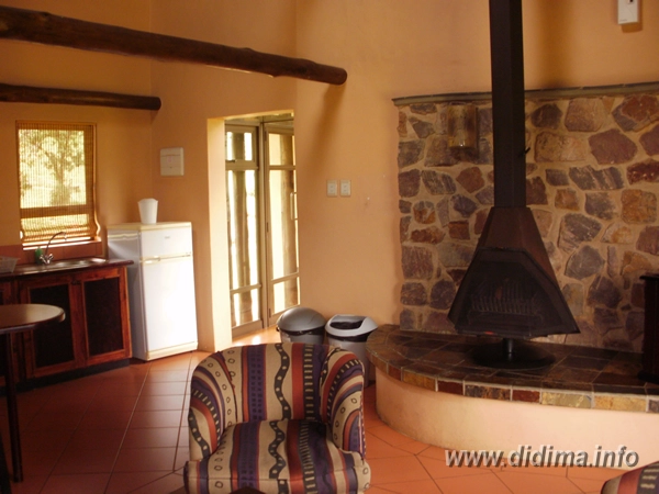 Living area with fireplace inside a four-sleeper self-catering chalet at Didima Camp