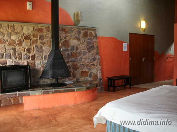 Living area and fireplace inside a two-sleeper chalet at Didima Camp