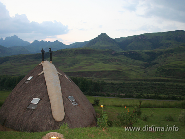 Thatched chalet rooftops overlooking the green Cathedral Peak Valley at Didima Camp